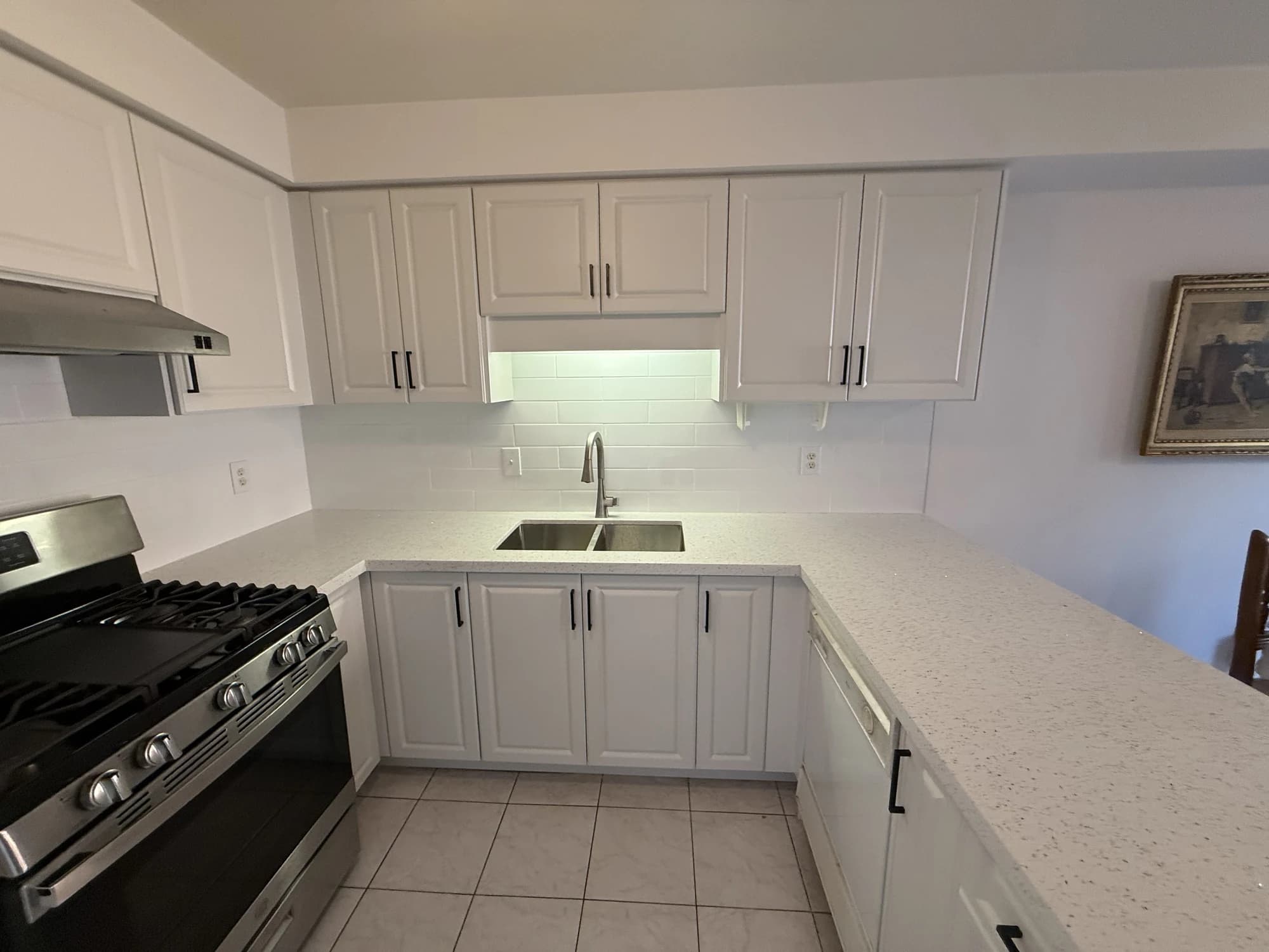 AFTER: bright kitchen following cabinet refacing, with new doors and drawer fronts, new countertop, new backsplash and updated dark hardware