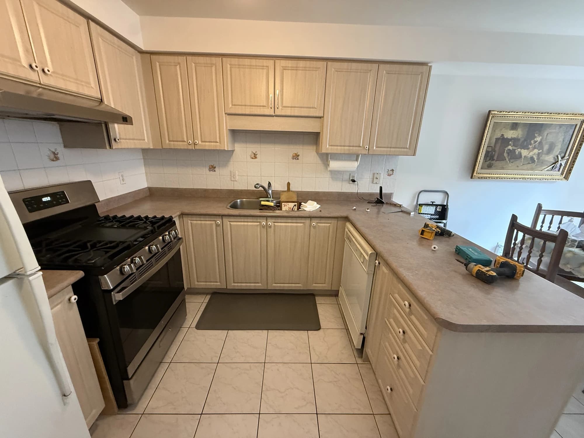 BEFORE: brown wood kitchen cabinets with the original doors, drawer fronts, countertop and tiled backsplash
